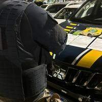 A imagem mostra um policial rodoviário federal em frente a viatura da instituição.
