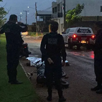 A imagem mostra policiais militares no local do acidente e o corpo da vítima e a motocicleta onde ela estava.
