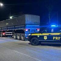 A imagem em destaque mostra uma viatura da Polícia Rodoviária Federal perto caminhão trator que estava carregado com a madeira