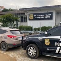 A imagem em destaque mostra uma viatura da Polícia Militar e outra da Polícia Civil em frente a Delegacia de Braço do Norte.