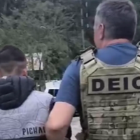 A imagem em destaque mostra o suspeito preso sendo conduzido por um policial civil.