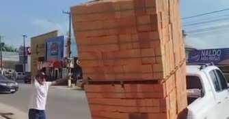 Homem se arrisca e tenta transportar duas pilhas de tijolos em carroceria de caminhonete; veja